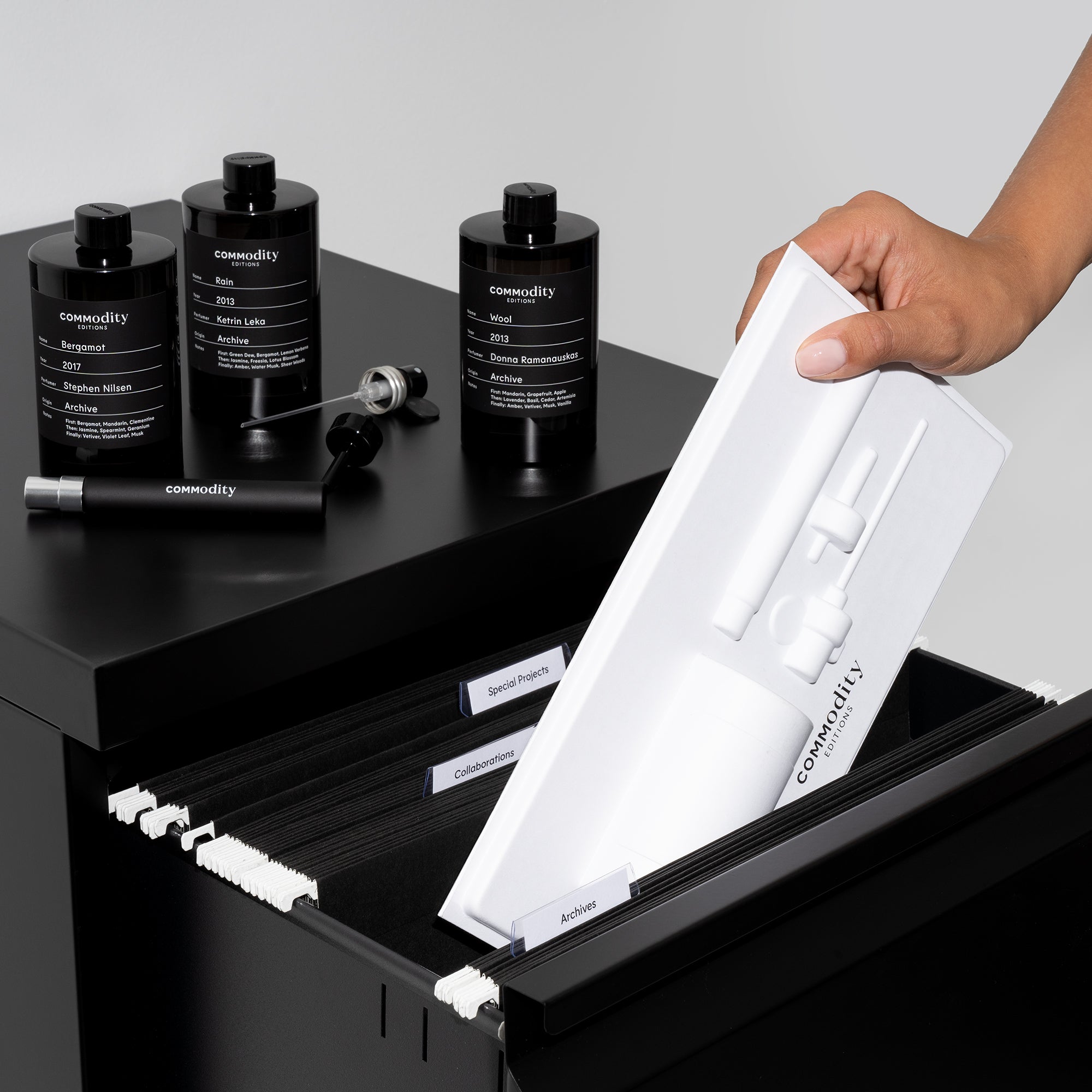 Diverse zwarte parfumflessen met refillpotlood en witte kaarthouder